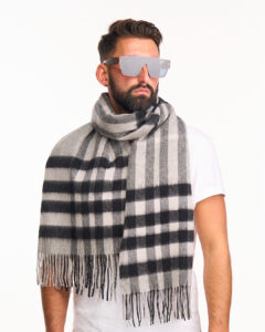 A premium navy and green tartan scarf draped over a luxury travel trunk, symbolising global reach and heritage.